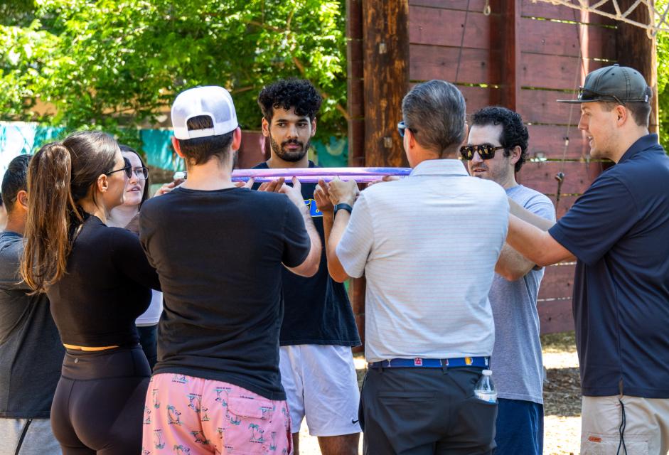 Professional programing out at the course in a circle playing a teambuilding game